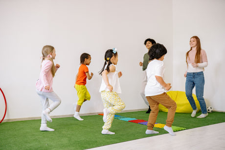 Grupo de niños pequeños haciendo actividades en una sala sobre una alfombra verde.